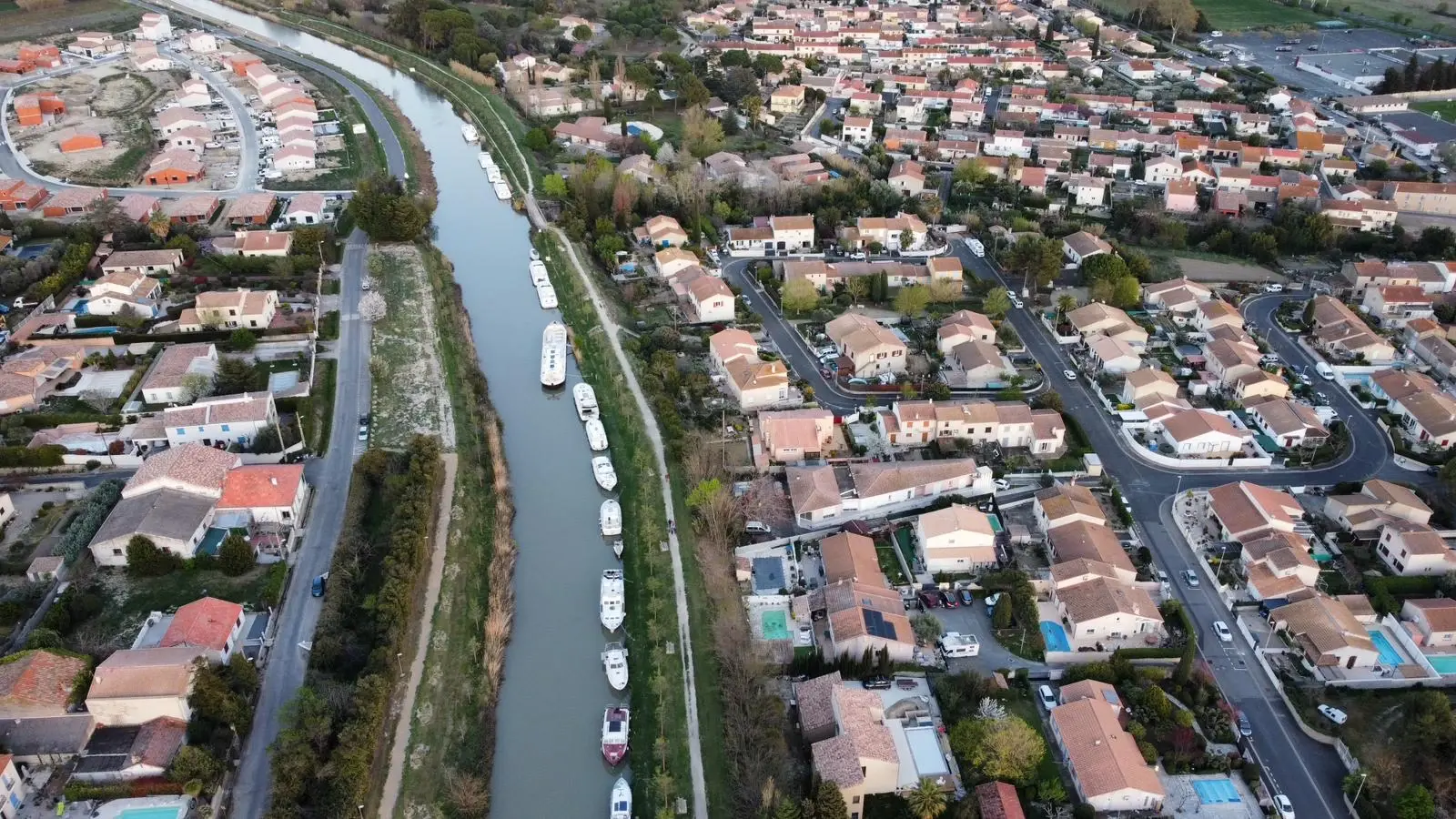 Vista aérea del canal con barcos amarrados en la orilla, entre las casas de un pueblo del sur de Francia