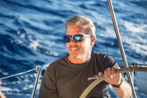 Joaquín Vazquez Prager, con gafas de sol, a la rueda del timón de un velero en alta mar