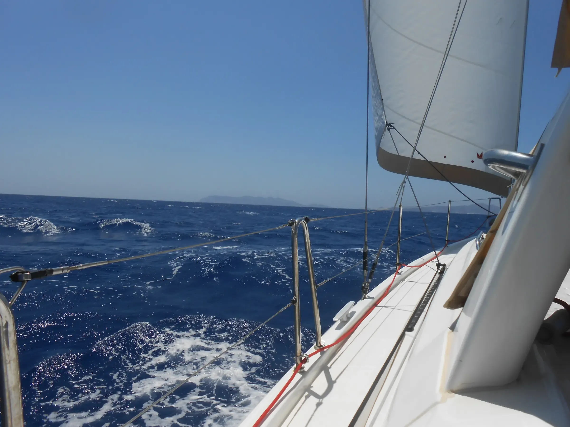 Velero escorado navegando con viento fresco por el Egeo, con la vela desplegada