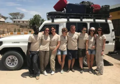 El equipo de la campaña posa junto a un todoterreno cargado de equipaje