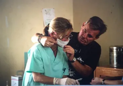 Una cirujana con mascarilla y un voluntario abrazados en el hospital
