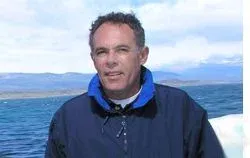 Salvador Capeta Alsina a bordo, con chaqueta de navegación y la costa al fondo