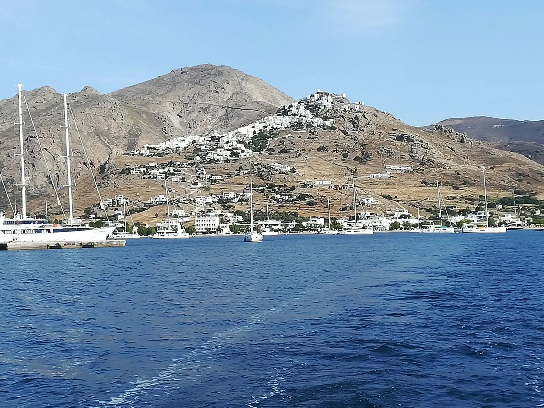 Vista de la costa de Serifos con su pueblo blanco en lo alto de la colina y veleros en el puerto